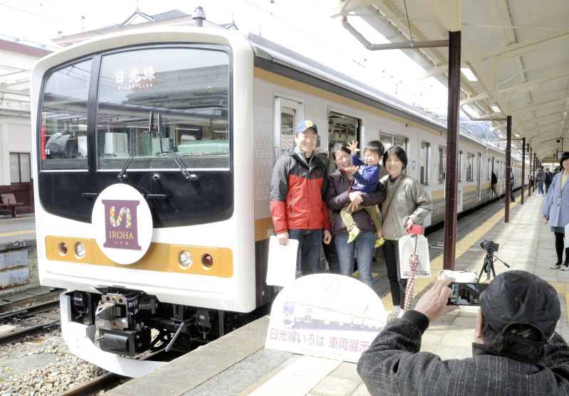 日光線の新車両「いろは」をバックに記念撮影する見物客=JR日光駅で