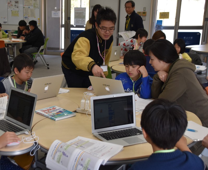 学生に教わりながらプログラムを組む子供たち