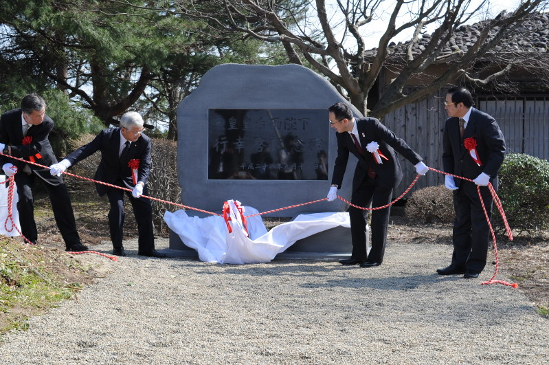 記念碑の除幕に臨む参加者ら=鶴岡市羽黒町の松ケ岡開墾場で