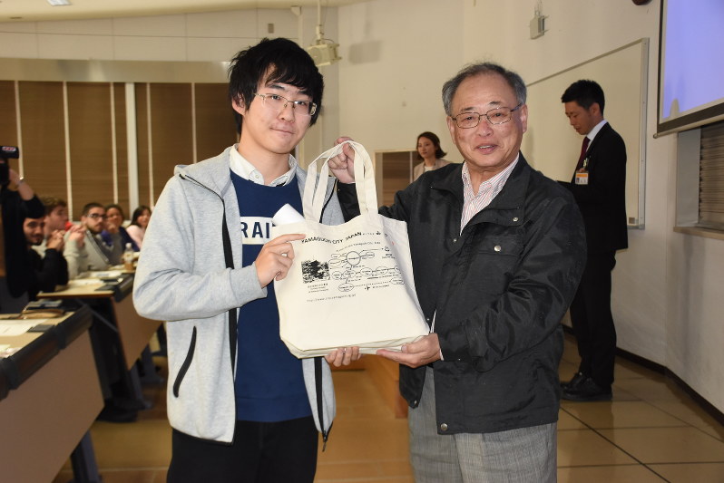 パックを受け取った留学生の張楽さん(左)と支援団体関係者