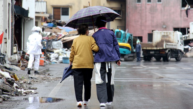 小雨の中、港周辺の被災地を寄り添いながら歩く人たち。住民相互の心のつながりがここでは生きている=岩手県釜石市で2011年5月28日