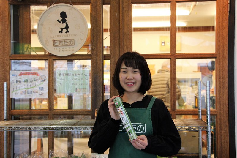 オリジナル商品「ほうれん草うどん」を手にする、店長の魚住さん=東京・国立市の八百屋「とれたの」前で