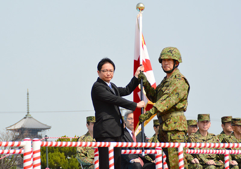 大野敬太郎防衛政務官(左)から隊旗を受け取る即応機動連隊の今井俊夫隊長=香川県善通寺市の陸上自衛隊善通寺駐屯地で、山中尚登撮影