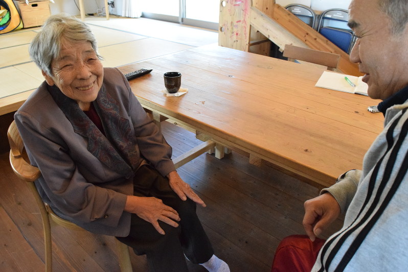 児成さん(右)にたしなめられ、笑ってごまかす西本さん。左膝を手のひらでさすり続けていた=熊本県甲佐町で、福岡賢正撮影