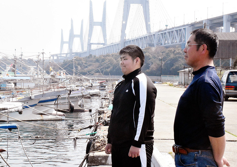 海を望む櫃本凌さん(左)と父英紀さん。背後に架かるのが瀬戸大橋=香川県坂出市の櫃石島で、小川和久撮影