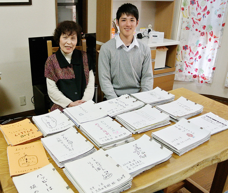 連載童話「読んであげて」のスクラップを前に笑顔を見せる大川多恵子さん(左)と孫の大川契也さん=大阪市福島区で、倉田陶子撮影