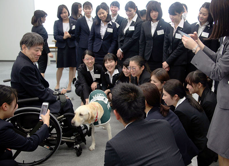 木村佳友さんと介助犬デイジーを囲んで話をする新入社員ら=大阪市北区の大阪第一生命ビルで、高尾具成撮影
