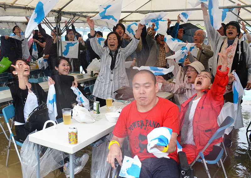 朝鮮半島が描かれたナプキンを投げる参加者たち=大阪市生野区の巽公園で、金志尚撮影