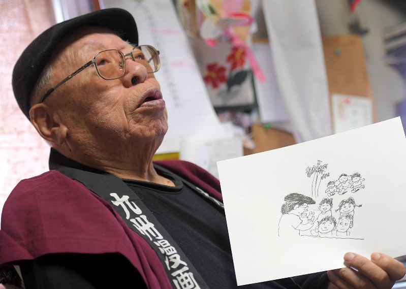 シリア訪問の様子を描いた自身の漫画について語る西山進さん=福岡市南区で