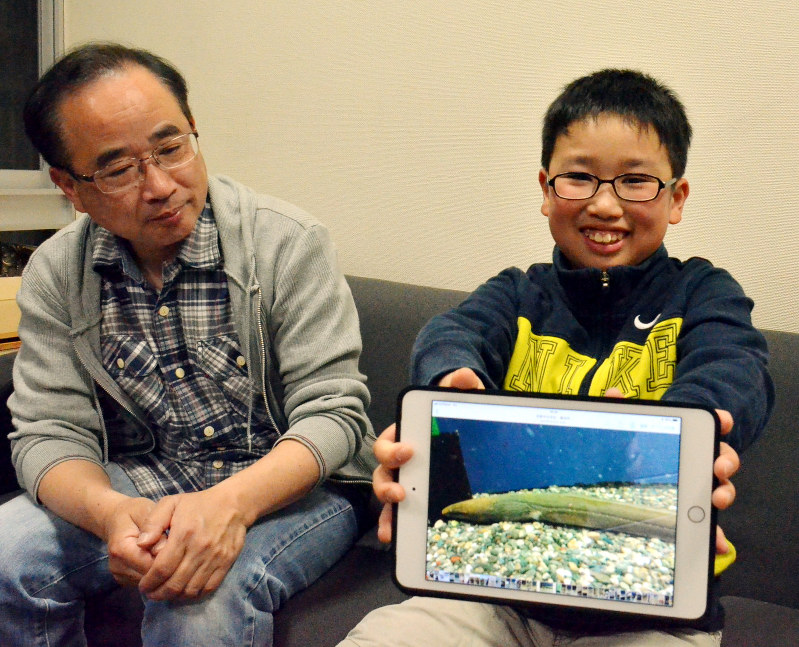 タブレット端末で飼育中の「カワウミヘビ」の写真を示す新谷隼平さん(右)と父哲也さん=京都市上京区で、大東祐紀撮影