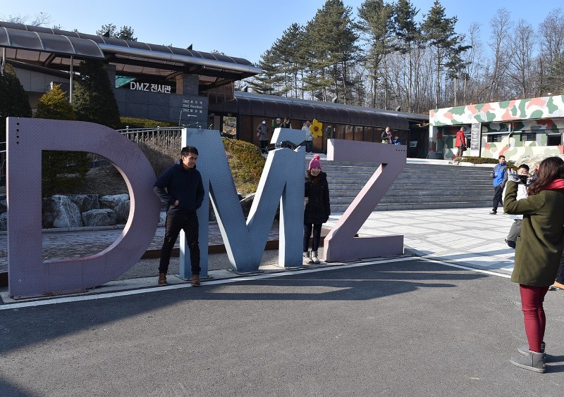 南侵第3トンネル前にある「DMZ」(非武装地帯)のモニュメントのそばで記念撮影する観光客=2015年12月、花松泰倫氏撮影
