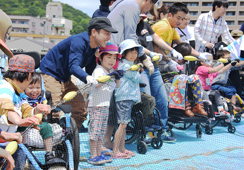 力を合わせて網を引く参加者たち=神戸市須磨区の須磨海岸で、黒川優撮影
