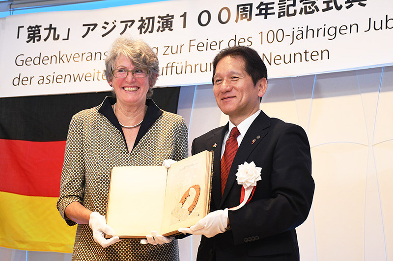 記念式典で徳島県鳴門市の泉理彦市長(右)に100年前の演奏会プログラムを手渡すペトラ・ボーナーさん=同市内で、大坂和也撮影