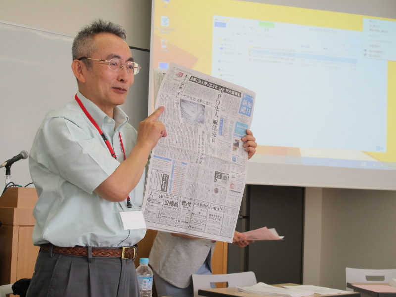 日本NPO学会で、NPO法人の売買問題を特報した毎日新聞を手に講演する関西学院大学の岡本仁宏教授=東京都豊島区の立教大学で2018年6月9日、太田誠一撮影