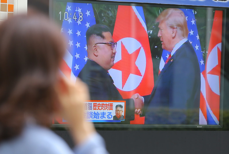 街頭テレビに映し出された米朝首脳会談を見つめる通行人=東京都千代田区で2018年6月12日午前10時48分、宮武祐希撮影