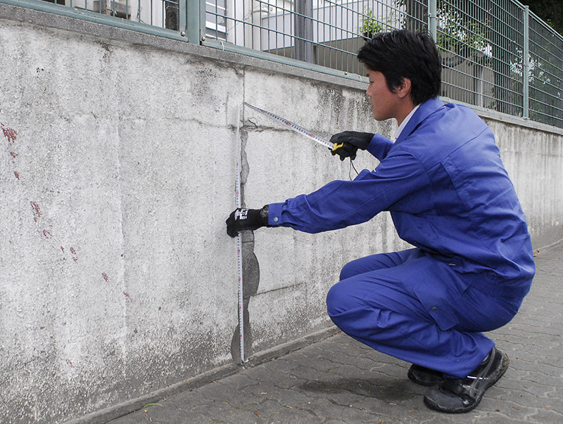 ブロック塀の高さを測定する兵庫県尼崎市教委の職員=同市名神町3の市立名和小学校で、近藤諭撮影