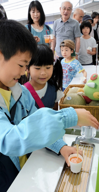 蛇口からメロンジュースを紙コップに注ぐ子供ら=福井市で