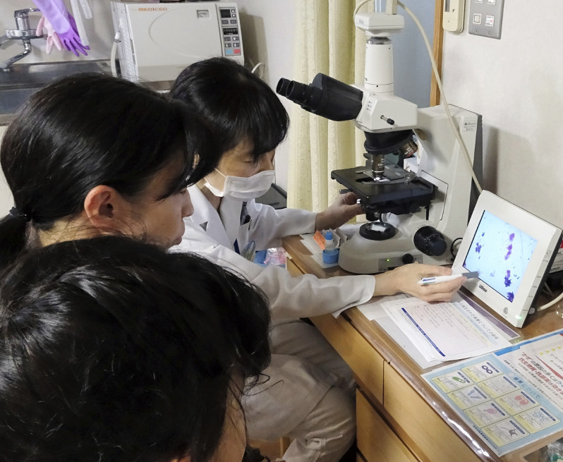 抗菌薬の処方が必要かどうかグラム染色の結果を聞く親子=奈良県橿原市のまえだ耳鼻咽喉科クリニックで(同クリニック提供)