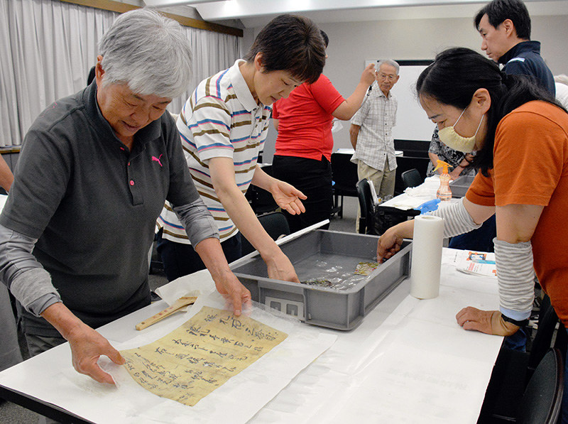 古文書や汚れた写真などを水洗いしてゴミを取り除く作業に挑む受講者ら=愛媛県西予市の県歴史文化博物館で、松倉展人撮影