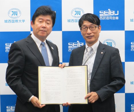 調印書を手にする杉林堅次学長（右）と落合寛司理事