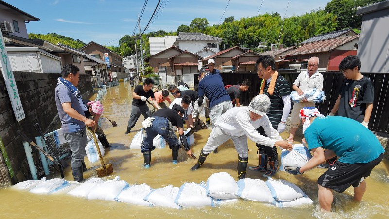 川の水が流れ込んだ住宅地で土のうを積む地域の住民=広島市安芸区矢野西で2018年7月9日午前10時28分、手塚耕一郎撮影