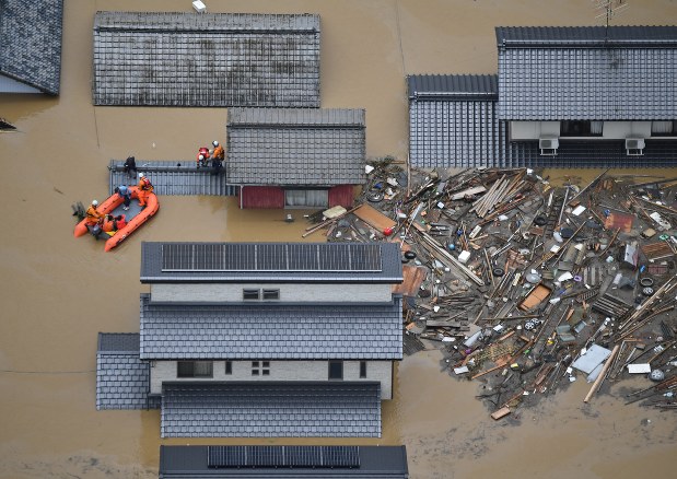 住宅の屋根に達する洪水に覆われた町で続けられる救助活動=岡山県倉敷市真備町で2018年7月7日、本社ヘリから加古信志撮影