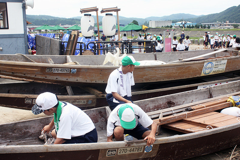 泥で汚れた遊覧船を拭く中学生たち=広島県三次市馬洗川の鵜飼乗船場で、岡本幸信撮影