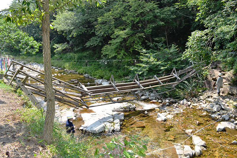 崩れて落ちたつり橋と、現状を調べる兵庫県職員=兵庫県西脇市住吉町で2018年7月17日午後1時56分、広田正人撮影