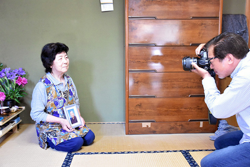 元船員の遺族を撮影する岡村啓佐さん(右)=高知県宿毛市で、松原由佳撮影