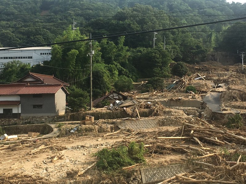 実家の向かい側の山で土砂崩れが起き、斜面は泥と流木とがれきで埋まっていた=7月13日筆者撮影
