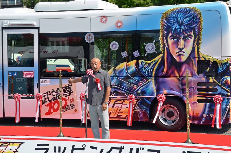 「北斗の拳」のキャラクターをデザインした市内循環バスの前で語る武論尊さん=佐久市で2018年7月22日午前9時6分、武田博仁撮影