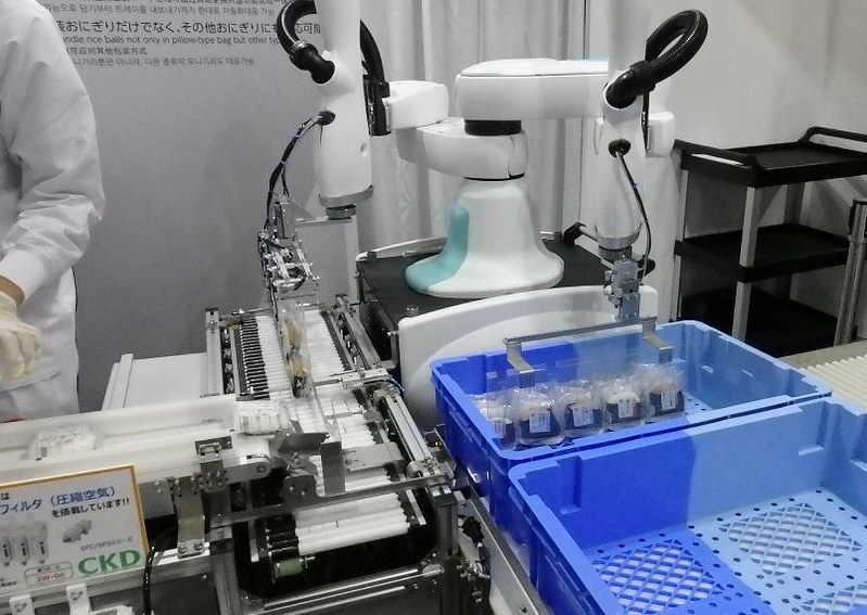 おにぎりを搬送用ケースに詰める川崎重工業のロボット=高橋慶浩撮影
