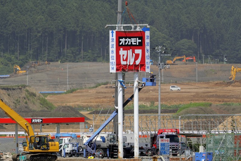 撤去作業が進むガソリンスタンド「オカモトセルフ陸前高田」の看板。周辺では今も復興に向けた造成工事が続く=岩手県陸前高田市で2018年7月31日午前10時2分、喜屋武真之介撮影