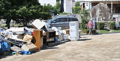 西日本豪雨で出た災害ゴミや土砂が仮置きされている公園に建つ原爆死没者の追悼碑＝広島市安芸区で２０１８年８月１日午前９時１１分、山崎一輝撮影