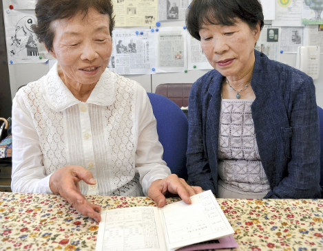 交付された被爆者健康手帳の記載内容を、妹（右）とともに確認する平山さん＝福岡市で２０１８年７月２０日、樋口岳大撮影