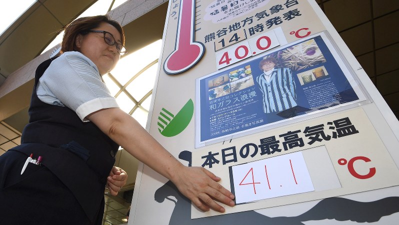 デパート前の気温掲示板の数字を張り替える女性。41度を超える想定をしておらず、手書きで作ったという=埼玉県熊谷市で2018年7月23日、丸山博撮影