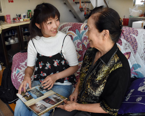 祖母スエ子さん（右）のアルバムを開きながら当時の話を聞く松永さん＝長崎市深堀町で２０１８年８月７日、今野悠貴撮影
