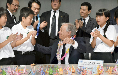 山里小の児童に習いながら作った折り鶴を手に笑顔を見せるグテレス事務総長（中央）＝長崎市の長崎原爆資料館で２０１８年８月９日午前９時１２分、青木絵美撮影
