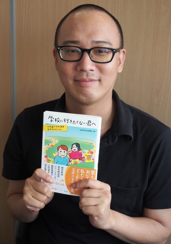 「学校に行きたくない君へ」を手にする不登校新聞の石井志昂編集長=東京都北区のNPO法人全国不登校新聞社で