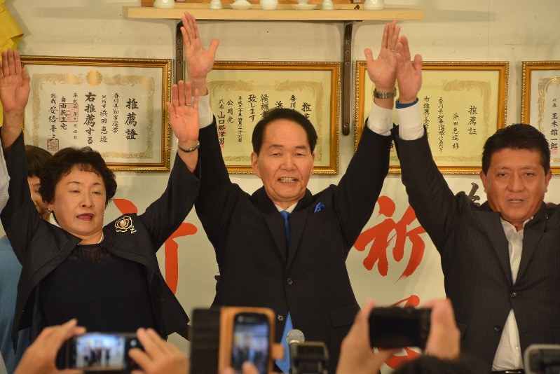当選が確実となりバンザイする浜田恵造氏(中央)=高松市で2018年8月26日午後8時3分、岩崎邦宏撮影