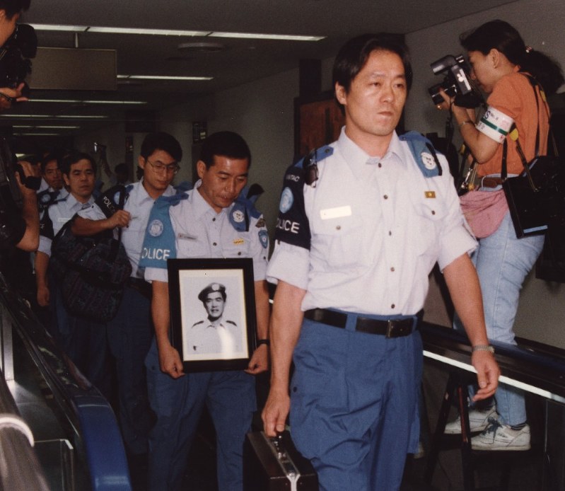高田晴行警視の遺影を抱え、カンボジアから帰国した日本人文民警察隊員。先頭は山崎裕人隊長=成田空港で1993年7月8日