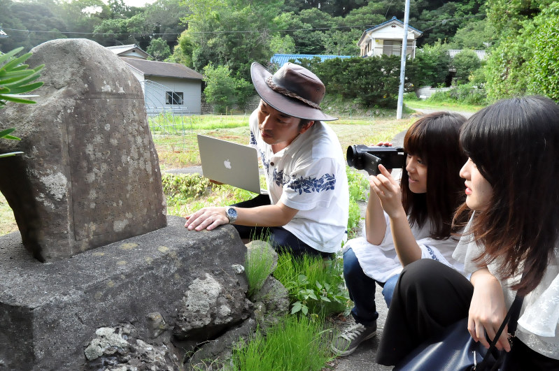 関東大震災の石碑を調査する東京成徳大の小薗崇明助教(左)と学生たち=千葉県南房総市で、宮本翔平撮影