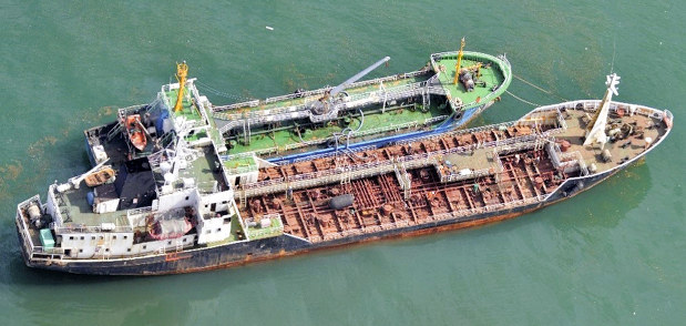 東シナ海の公海上で船籍不明のタンカー(上)に横付けし、蛇管をつなぐ北朝鮮船籍のタンカー=2018年5月24日(防衛省提供)