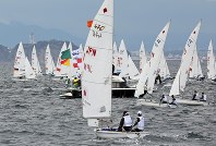 ２０２０年東京五輪の初のテスト大会となるセーリングＷ杯の競技が始まり、江の島（左奥）沖にいろいろな国旗をあしらったヨットが走った＝神奈川県・江の島沖で２０１８年９月１１日午後０時６分、梅村直承撮影
