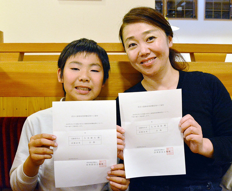 防災士試験の合格通知を手にする久本康太さん(左)と母美保さん=高松市内で、岩崎邦宏撮影