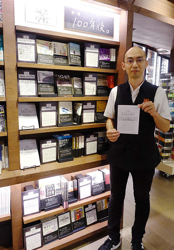 「読書の学校」の書棚前でリーフレットを手にする梅田蔦屋書店の三砂慶明さん=大阪市北区で、須藤唯哉撮影