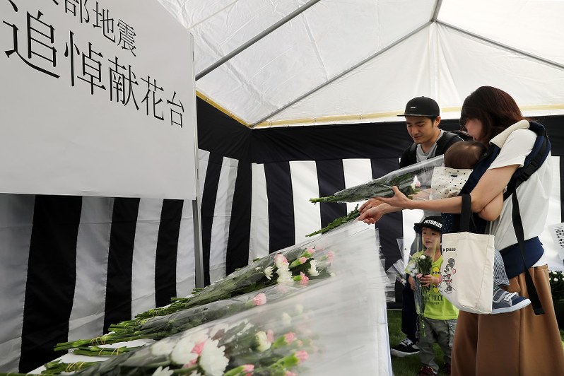 町役場前に設置された犠牲者追悼献花台に花束を供える家族連れ=北海道厚真町で2018年9月15日午後0時10分、貝塚太一撮影