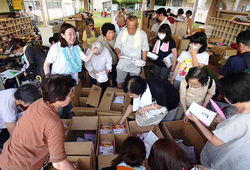 豪雨が起きた直後、避難所には多くの人が詰め掛けた。支援物資が届くと、たくさんの手が伸びた=岡山県倉敷市真備町地区の岡田小学校で2018年7月9日、平川義之撮影