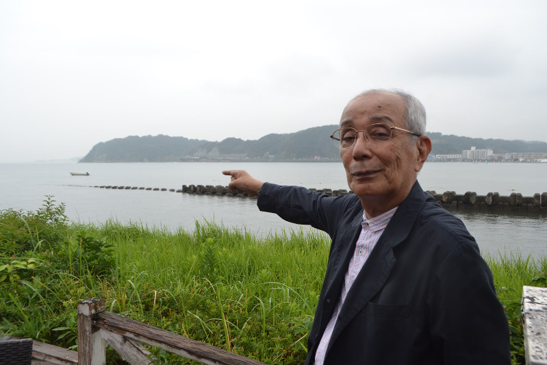 「岬巡りは日本列島をなぞる作業。国土の端っこで頑張っている姿がいとおしい」。逗子湾に面する大崎を指さしながらそう話す大江高司さん=神奈川県逗子市で、上東麻子撮影