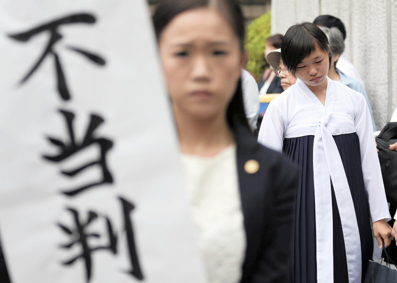 垂れ幕を掲げる弁護士の後ろで肩を落とす大阪朝鮮高級学校の生徒たち=大阪市北区の大阪高裁前で2018年9月27日午後3時6分、小出洋平撮影